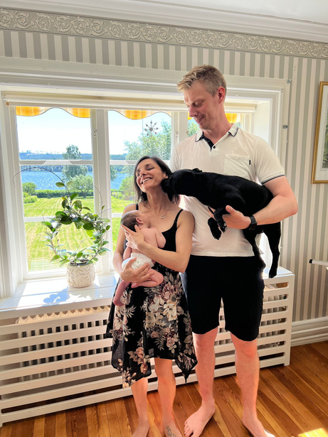 Vår familj bestående av Vania, Staffan, vår dotter som då var nyfödd, och vår hund. Vi står i matsalen i vårt hem, Långnäs Herrgård, med trädgården och sjön Stor-Gösken i bakgrunden. 